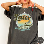 Comfort Colors tee in Pepper featuring vintage style graphic of an alligator emerging from water with sunset background