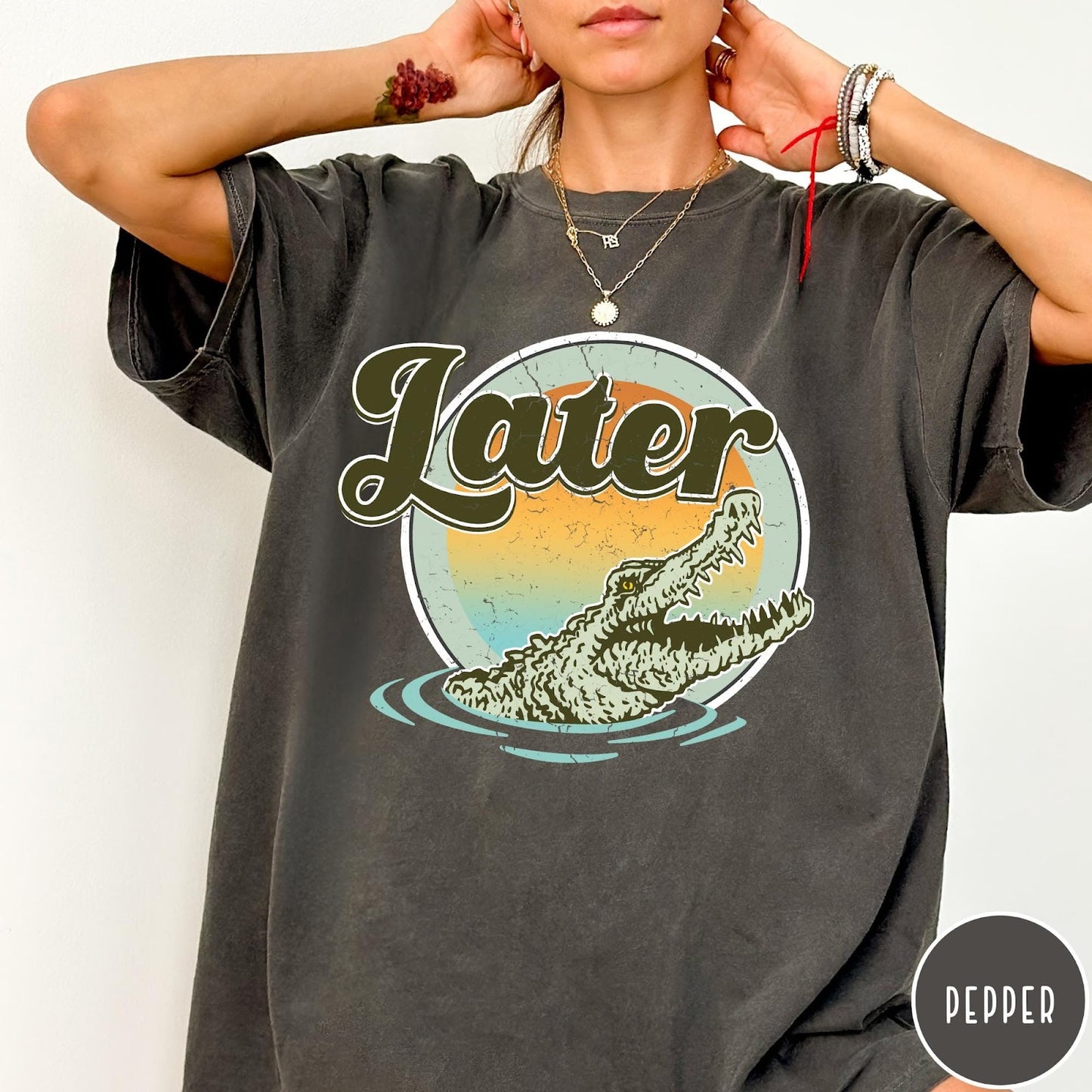 Comfort Colors tee in Pepper featuring vintage style graphic of an alligator emerging from water with sunset background