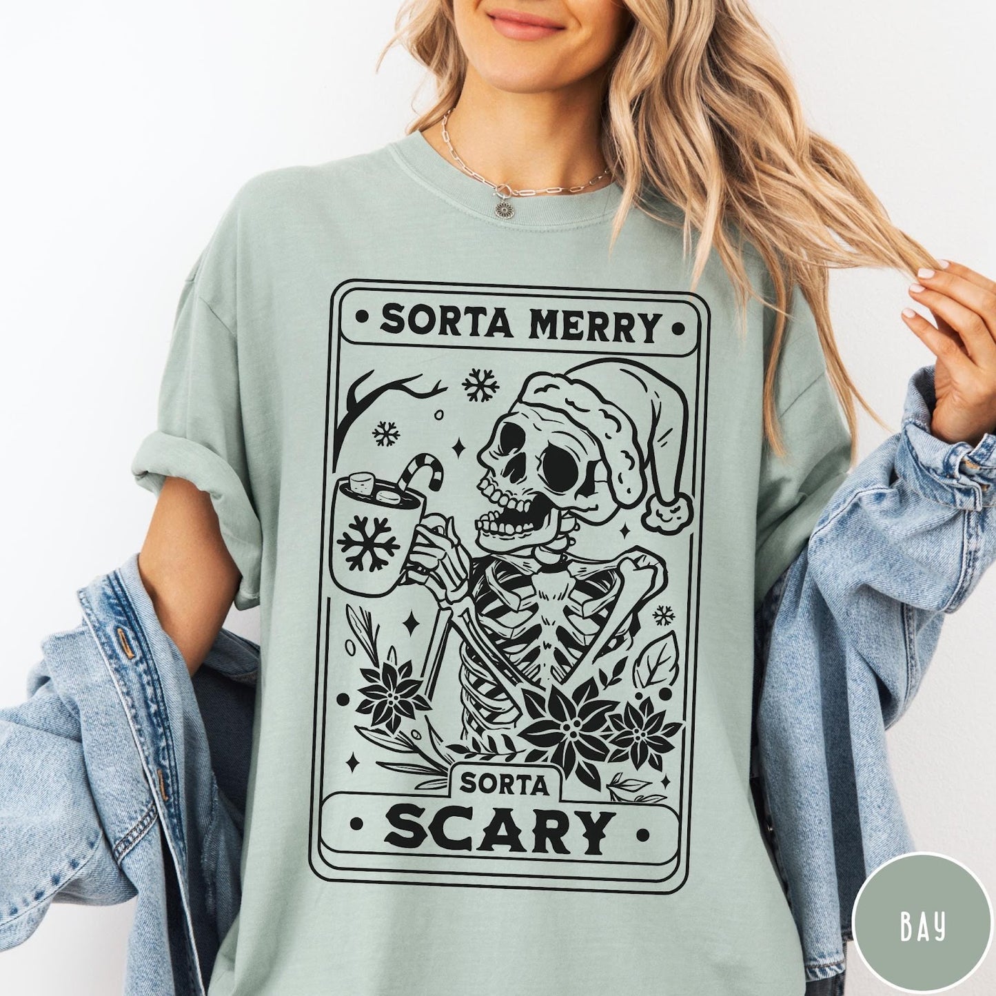 Comfort Colors tee in Bay featuring graphic illustration of a skeleton in a Santa hat holding cocoa