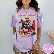 Comfort Colors tee in Orchid featuring western style graphic of a cowgirl riding a horse in desert