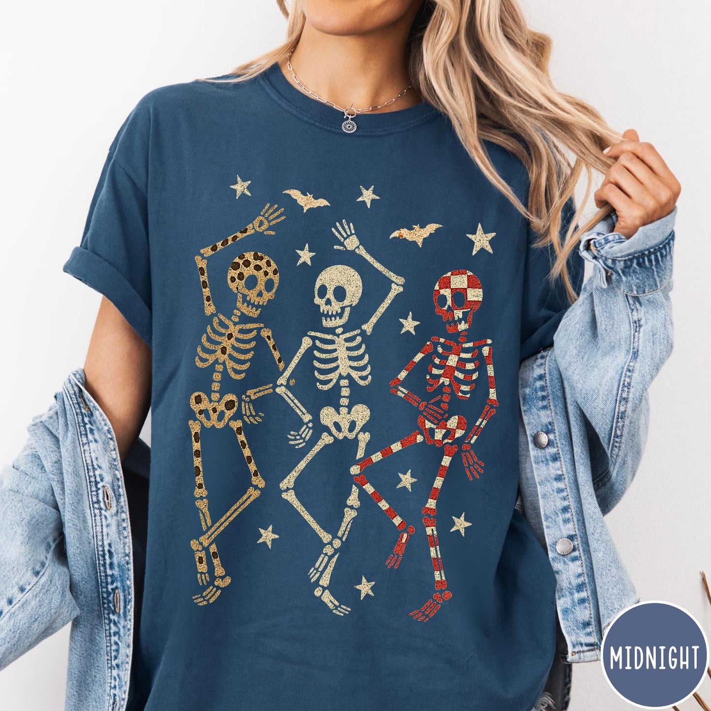 Comfort Colors tee in Midnight featuring dancing skeletons design with three skeletons, stars, and bats graphic