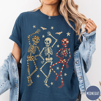 Comfort Colors tee in Midnight featuring dancing skeletons design with three skeletons, stars, and bats graphic