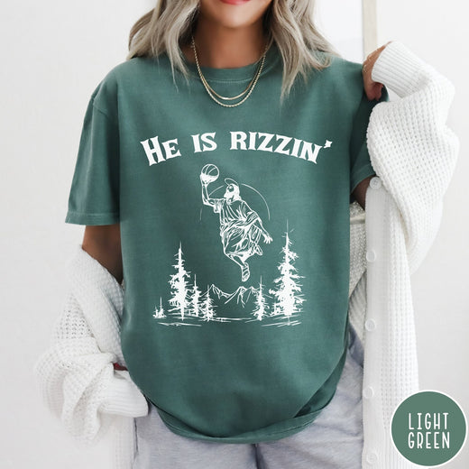 Comfort Colors tee in Light Green featuring graphic style Jesus playing basketball with mountains and pine trees illustration
