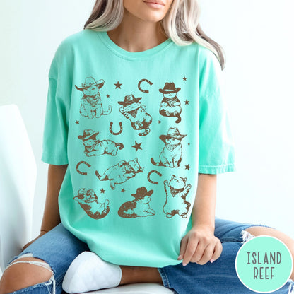 Comfort Colors tee in Island Reef featuring western graphic style with multiple cowboy kittens and horseshoe illustrations