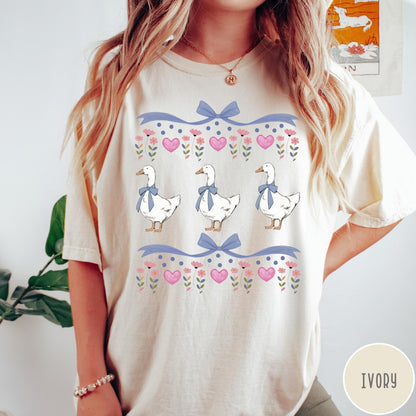 Comfort Colors tee in Ivory featuring vintage style graphic with three geese wearing blue bows and hearts
