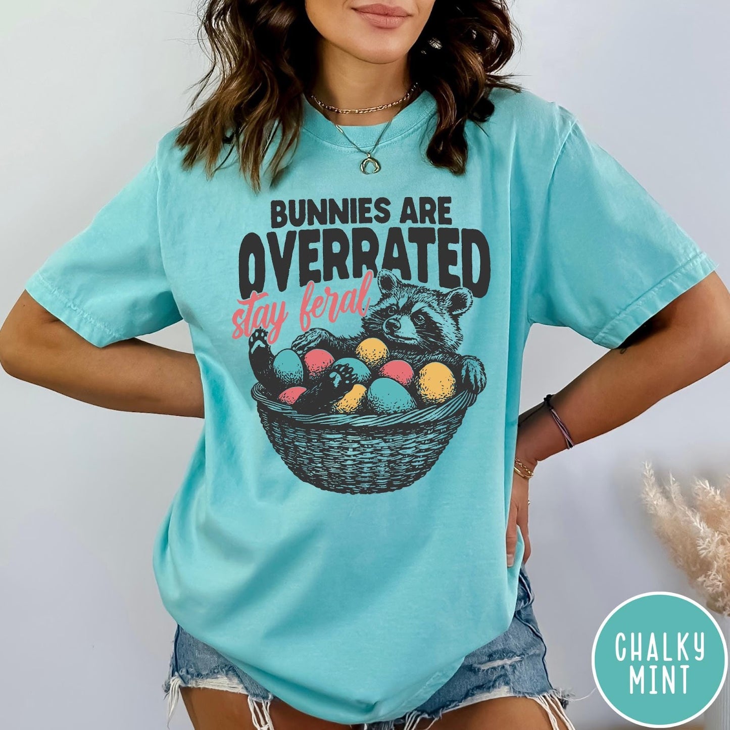 Comfort Colors tee in Chalky Mint featuring graphic illustration of a raccoon sitting in an Easter basket