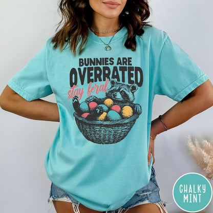 Comfort Colors tee in Chalky Mint featuring graphic illustration of a raccoon sitting in an Easter basket