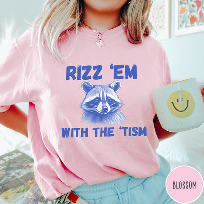 Comfort Colors tee in Blossom featuring screen printed raccoon graphic and Rizz Em With the Tism text