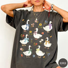 Comfort Colors tee in Pepper featuring vintage style graphic of several white geese wearing colorful bows and flowers