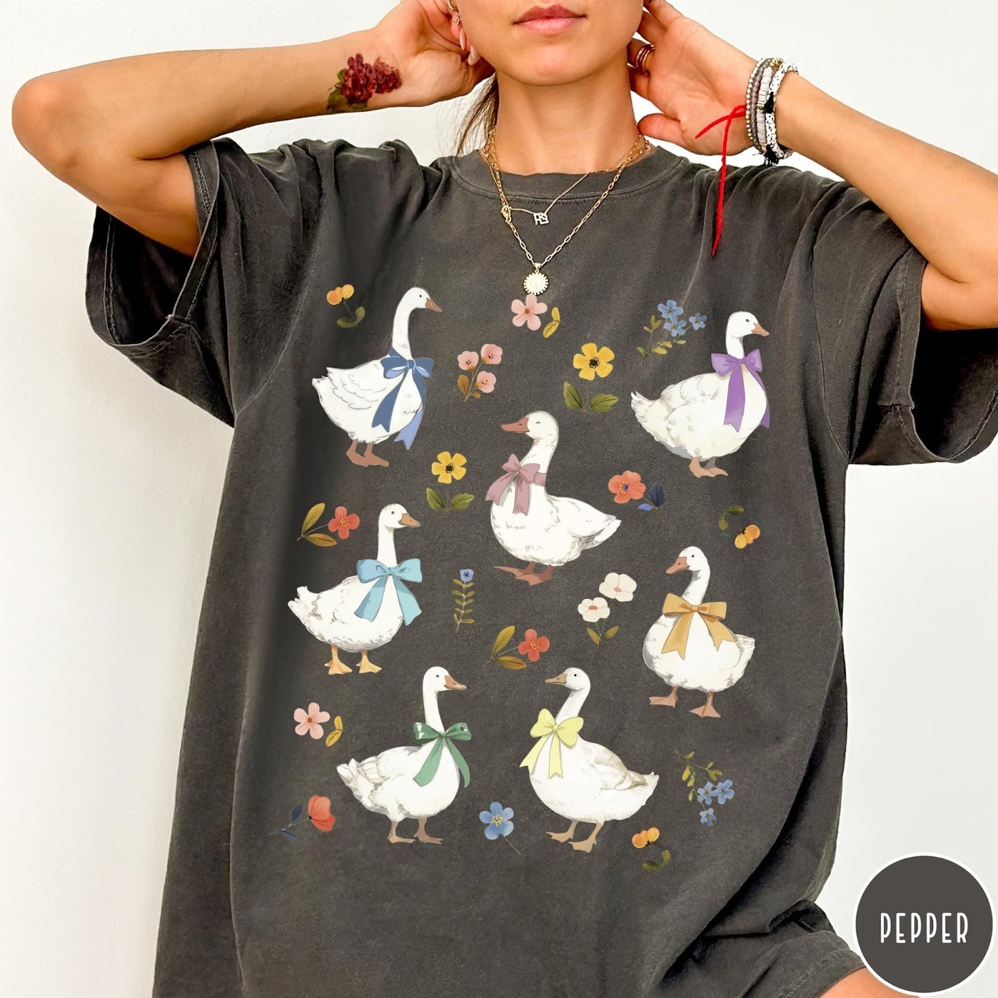 Comfort Colors tee in Pepper featuring vintage style graphic of several white geese wearing colorful bows and flowers