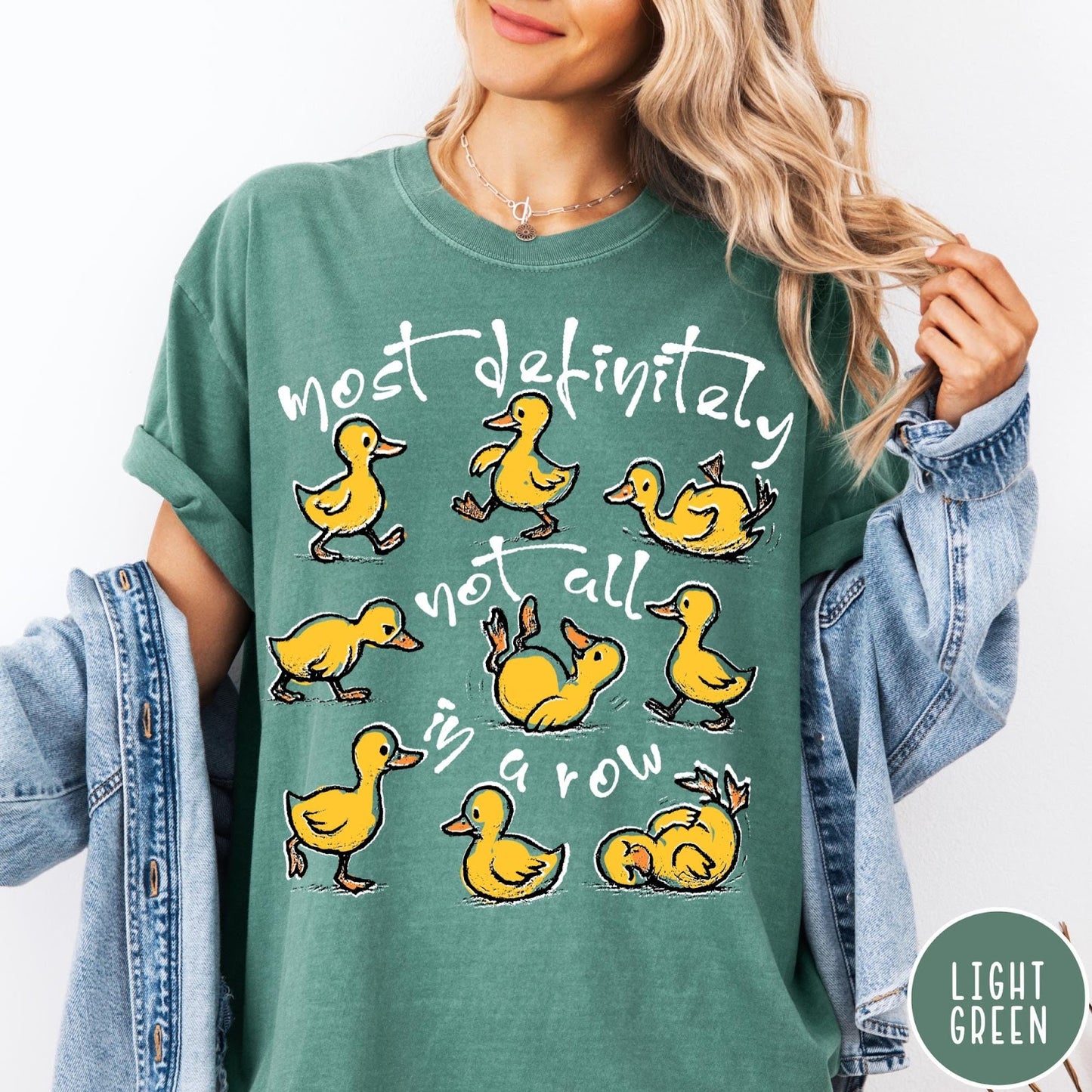 Comfort Colors tee in Light Green featuring screen print style graphic of nine yellow ducks in various poses