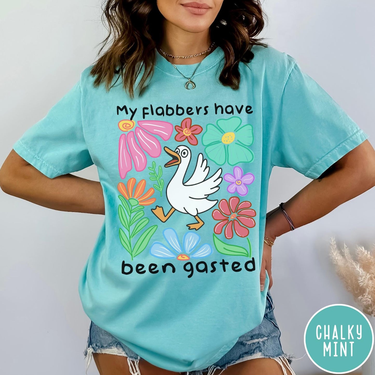 Comfort Colors tee in Chalky Mint featuring playful cartoon style graphic of a goose surrounded by colorful flowers