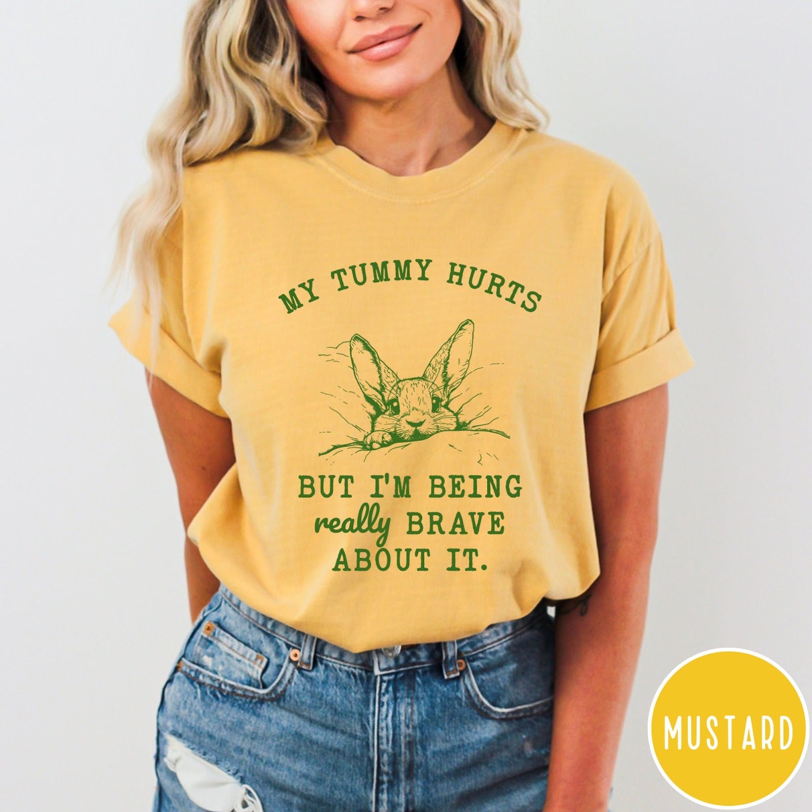 Comfort Colors tee in Mustard featuring line art graphic of a bunny with text My Tummy Hurts
