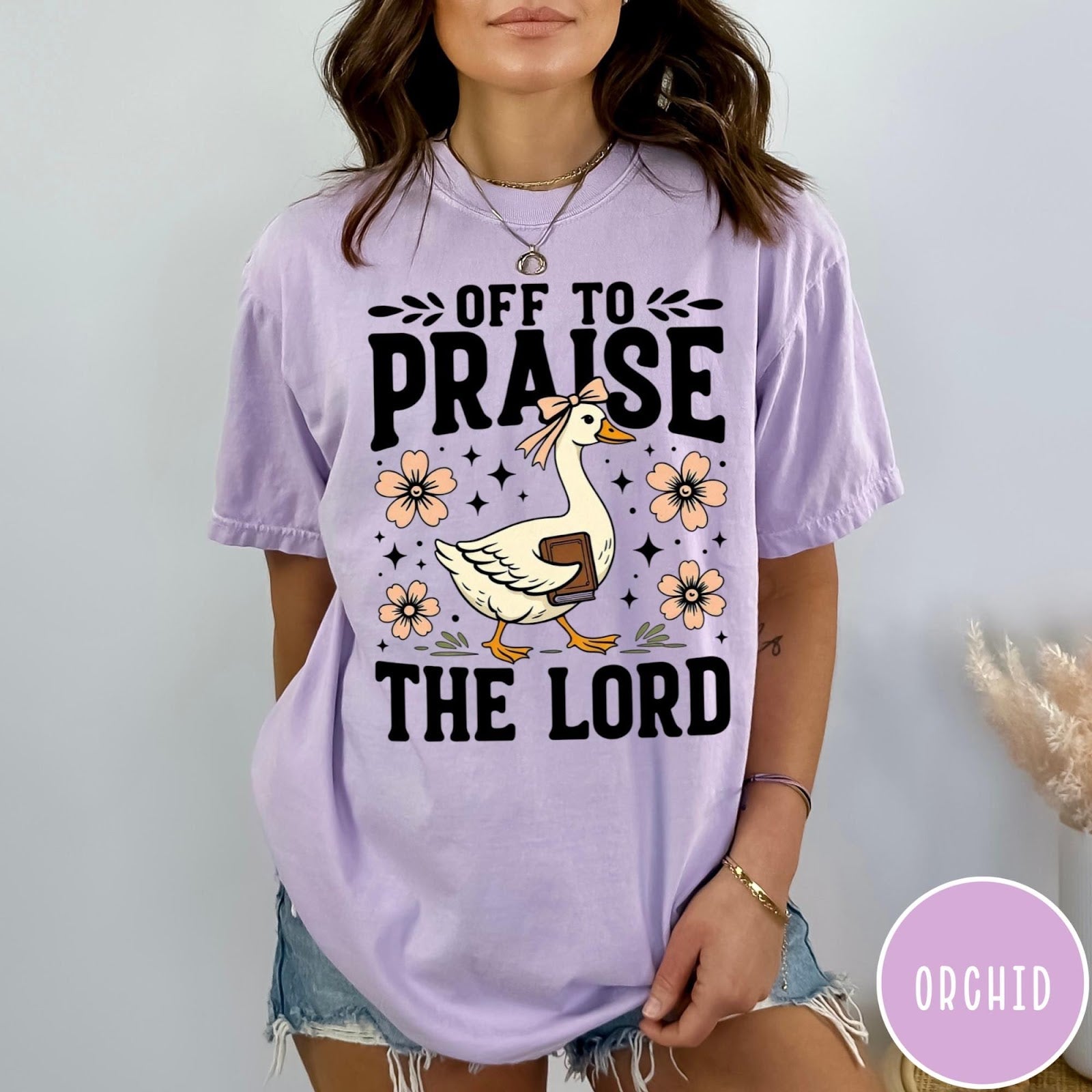 Comfort Colors tee in Orchid featuring retro style graphic of a goose wearing a bow holding a book