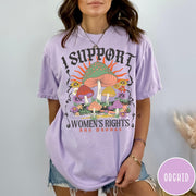 Comfort Colors tee in Orchid featuring retro style graphic with mushrooms, flowers, and sun with inspirational text