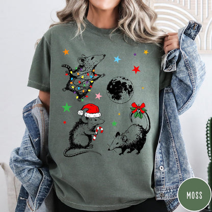 Comfort Colors tee in Moss featuring holiday possum graphic with Christmas lights, candy cane, and moon.