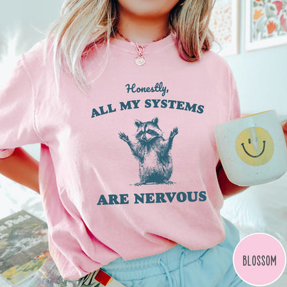 Comfort Colors tee in Blossom featuring graphic illustration of a nervous raccoon with arms raised in air
