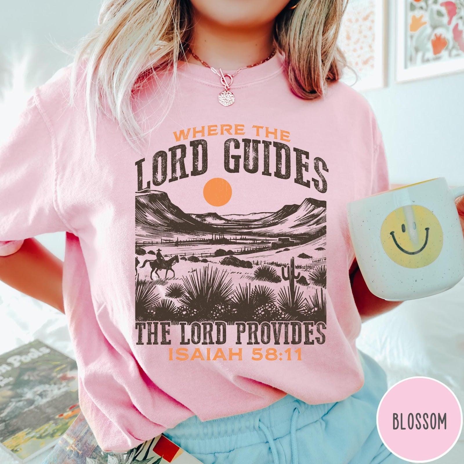 Comfort Colors tee in Blossom featuring desert landscape graphic with a rider and sun design.