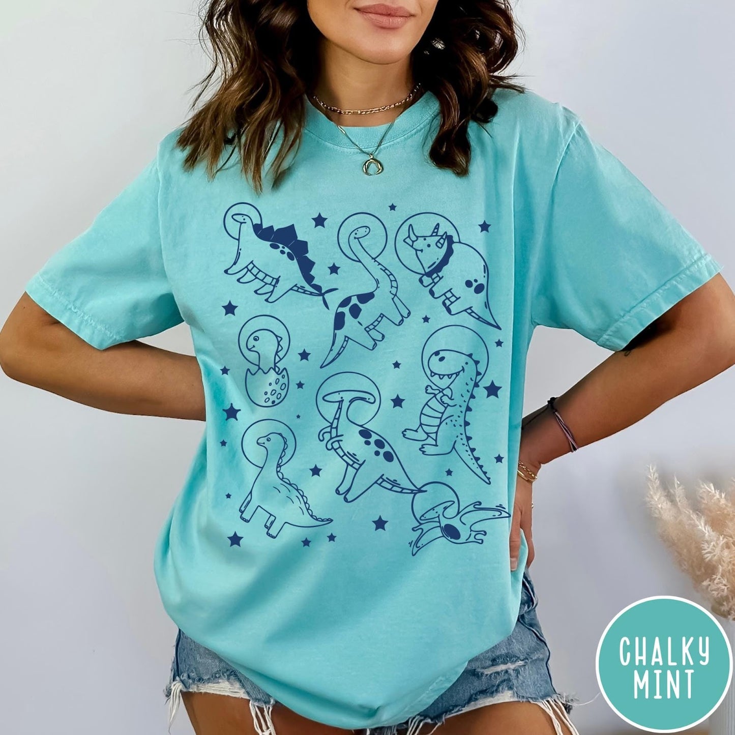 Comfort Colors tee in Chalky Mint featuring line art graphic of various dinosaurs wearing astronaut helmets in space