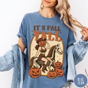 Comfort Colors tee in Blue Jean featuring western graphic of a pumpkin cowgirl riding a skeleton horse with pumpkins