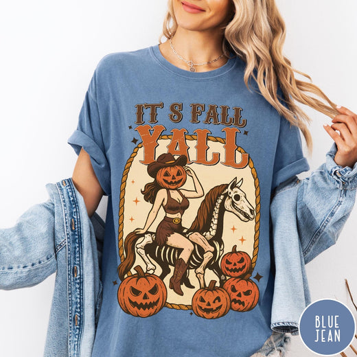 Comfort Colors tee in Blue Jean featuring western graphic of a pumpkin cowgirl riding a skeleton horse with pumpkins