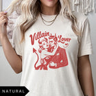 Comfort Colors tee in Natural featuring vintage style graphic of a devilish couple embracing with text Villain Lover