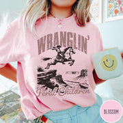 Comfort Colors tee in Blossom featuring western style graphic of a cowboy on horseback jumping a canyon