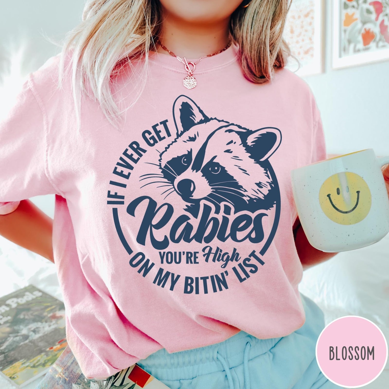 Comfort Colors tee in Blossom featuring screen print style graphic of a raccoon with funny rabies text