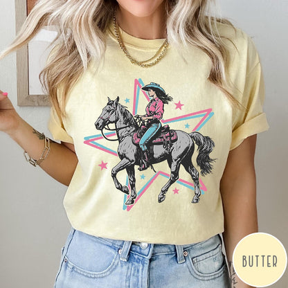 Comfort Colors tee in Butter featuring retro cowgirl graphic with a woman riding a horse inside a star