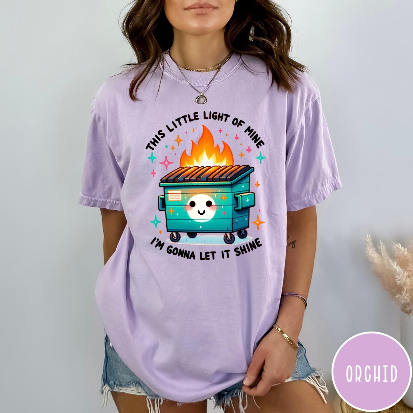 Comfort Colors tee in Orchid featuring cartoon style graphic of a smiling dumpster fire with text