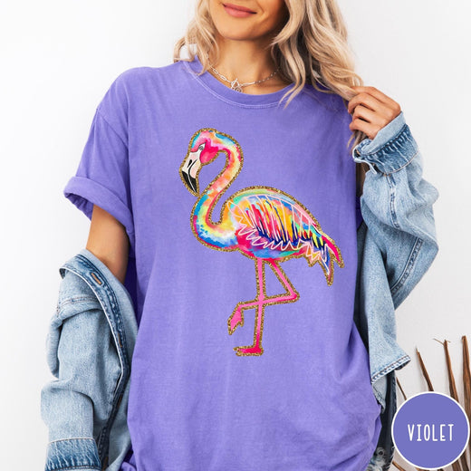 Comfort Colors tee in Violet featuring artistic watercolor flamingo graphic with gold glitter outline details