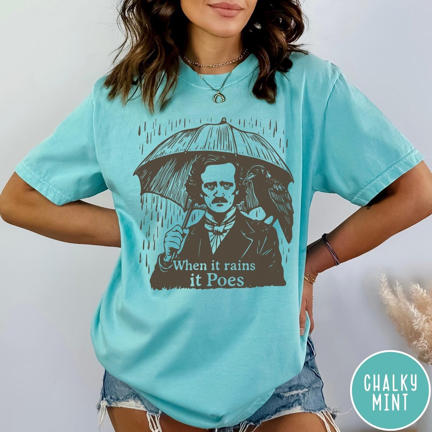Comfort Colors tee in Chalky Mint featuring graphic illustration of Edgar Allan Poe with umbrella and raven