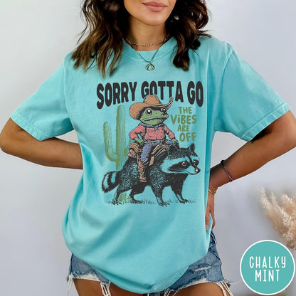 Comfort Colors tee in Chalky Mint featuring western graphic of a cowboy frog riding a raccoon with cactus