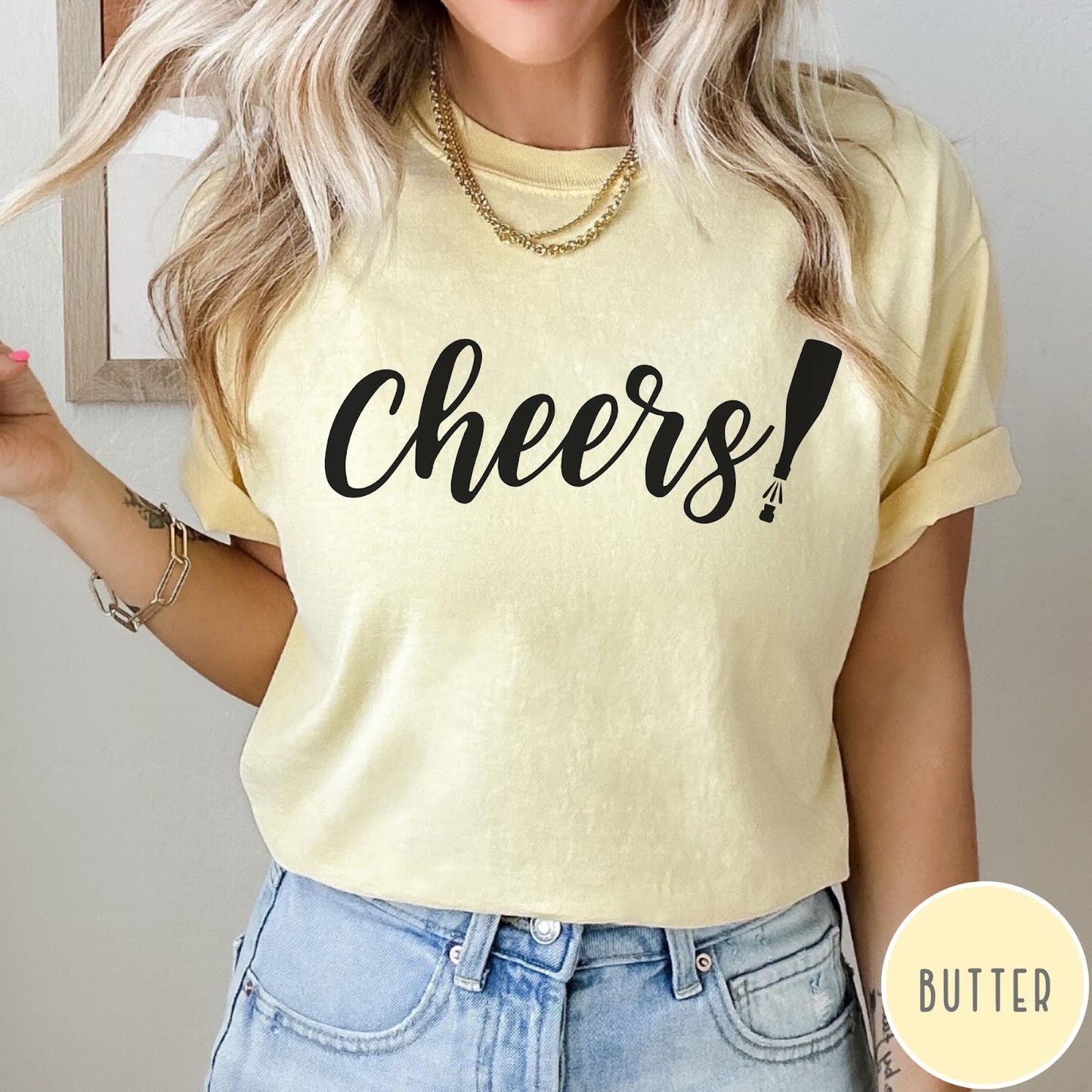 Comfort Colors tee in Butter featuring New Year celebration graphic with black cheers text and champagne bottle
