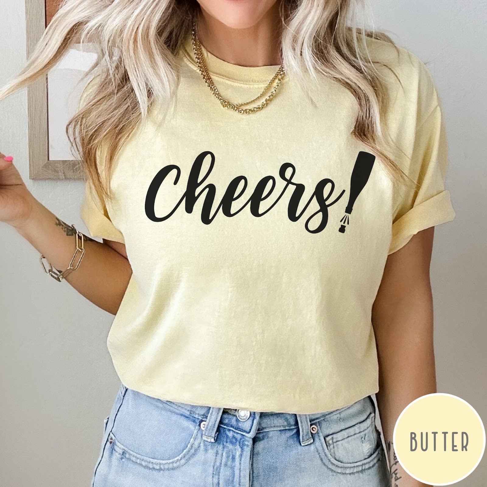 Comfort Colors tee in Butter featuring New Year celebration graphic with black cheers text and champagne bottle