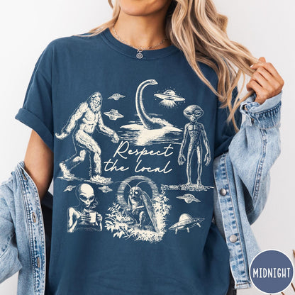 Comfort Colors tee in Midnight featuring vintage style cryptid graphic with Bigfoot, UFOs, and alien creatures.