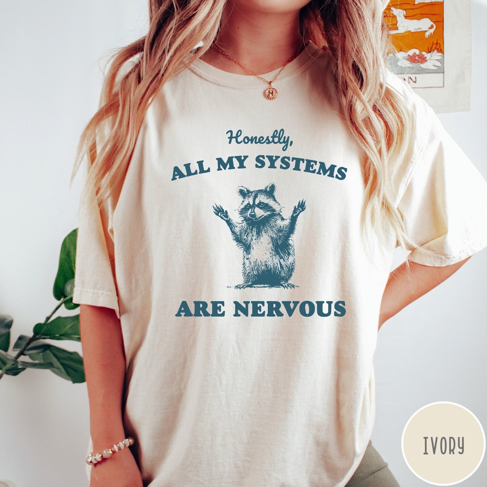 Comfort Colors tee in Ivory featuring graphic illustration of a nervous raccoon with arms raised in air