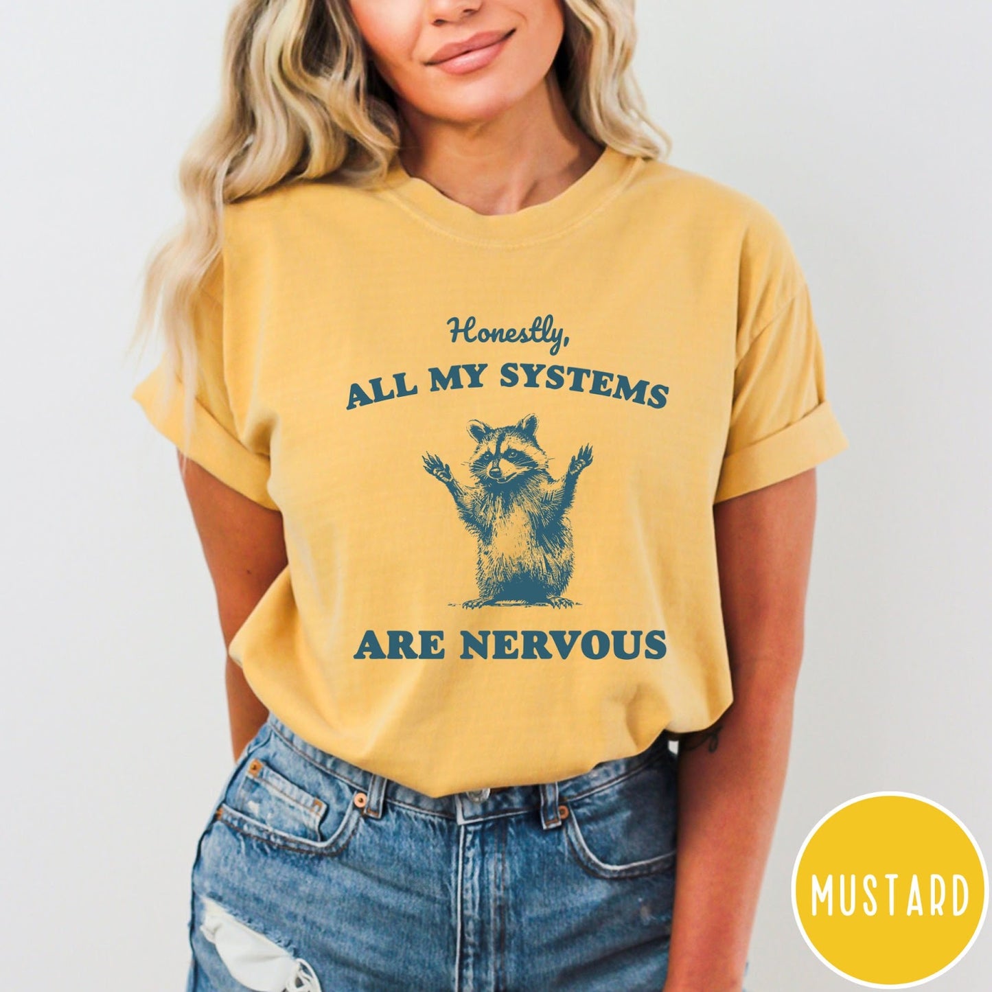 Comfort Colors tee in Mustard featuring graphic illustration of a nervous raccoon with arms raised in air