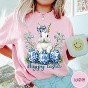 Comfort Colors tee in Blossom featuring Easter bunny graphic with blue floral bow and patterned Easter eggs