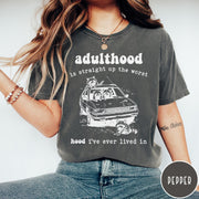 Comfort Colors tee in Pepper featuring illustrated style graphic of raccoons sitting in and around a car