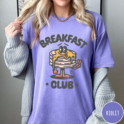 Comfort Colors tee in Violet featuring retro style graphic of a pancake character with syrup and peace sign
