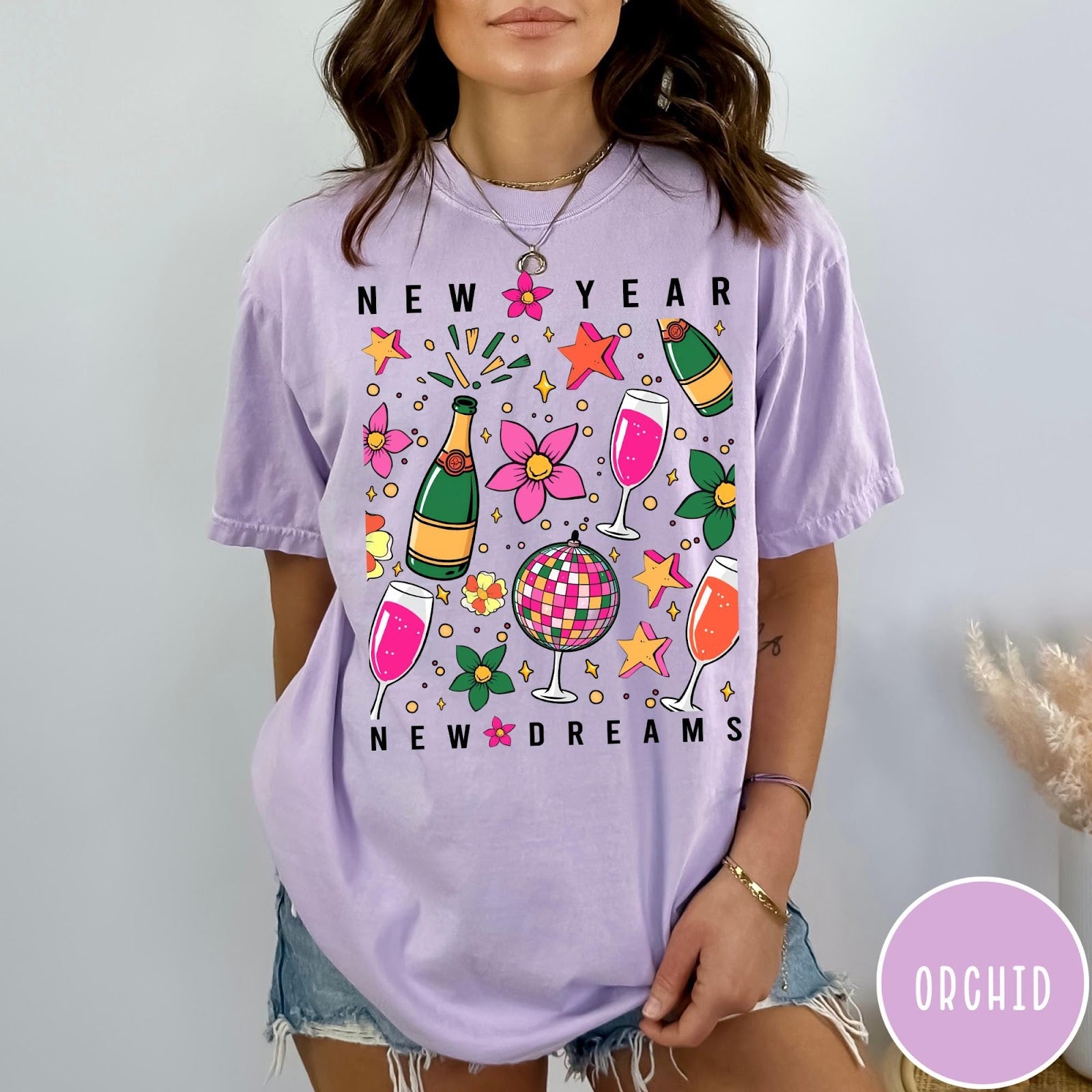 Comfort Colors tee in Orchid featuring New Year celebration graphic with champagne bottles, glasses, and disco ball