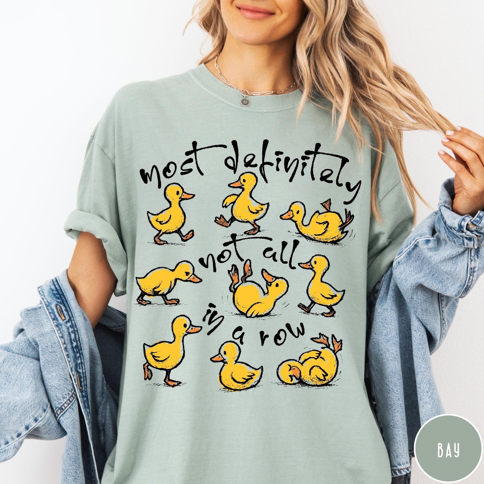 Comfort Colors tee in Bay featuring whimsical duck graphic with text most definitely not all in a row.
