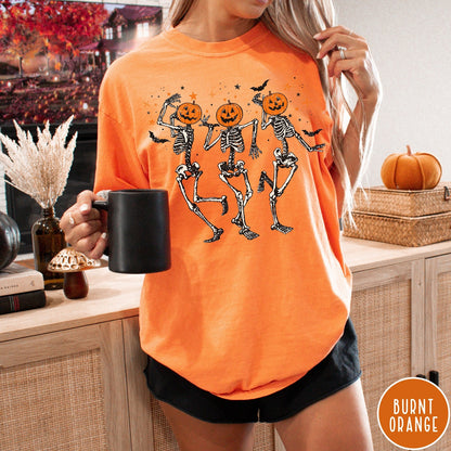 Comfort Colors tee in Burnt Orange featuring dancing skeleton graphic with jack-o'-lantern heads and small orange stars