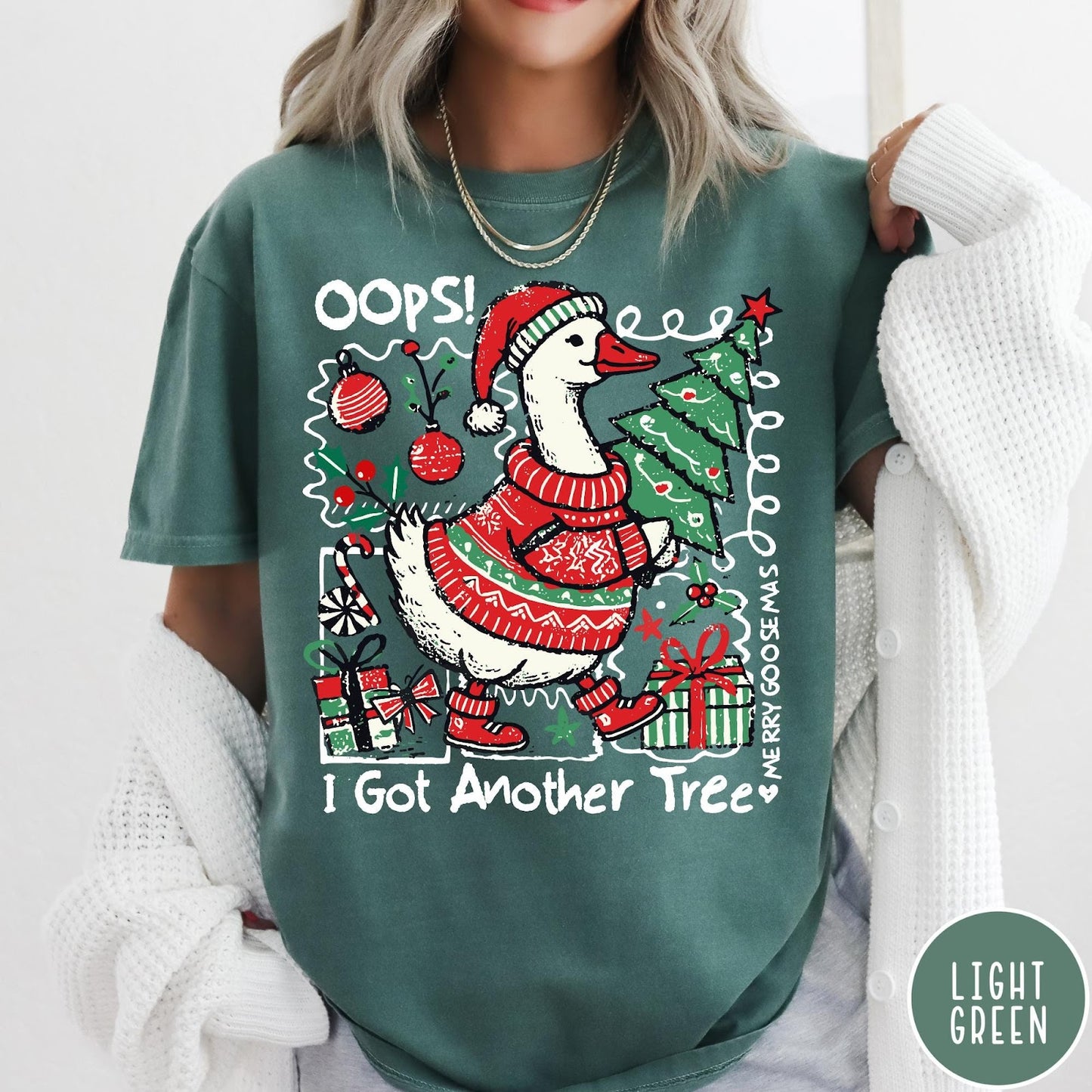 Comfort Colors tee in Light Green featuring festive goose graphic wearing a Santa hat and Christmas sweater holding tree