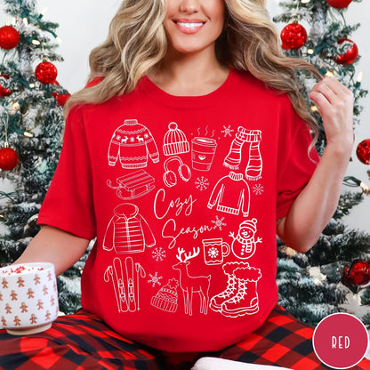 Comfort Colors tee in Red featuring winter activities graphic with sweaters, sled, snowman, and seasonal items.