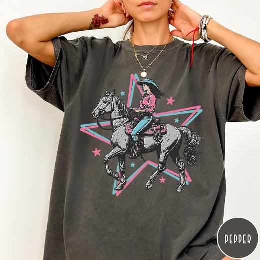 Comfort Colors tee in Pepper featuring retro cowgirl graphic with a woman riding a horse inside a star
