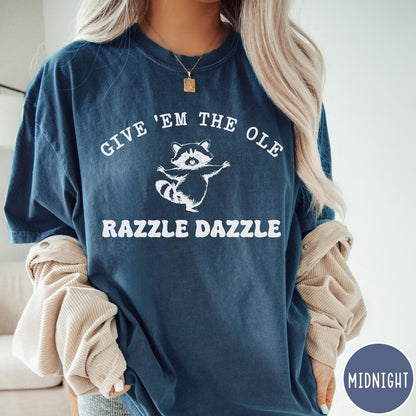 Comfort Colors tee in Midnight featuring whimsical raccoon graphic with Give Em The Ole Razzle Dazzle text