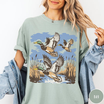 Comfort Colors tee in Bay featuring vintage style mallard ducks flying over a marshy pond graphic