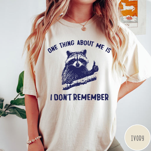 Comfort Colors tee in Ivory featuring screen print style graphic of a raccoon giving a thumbs up